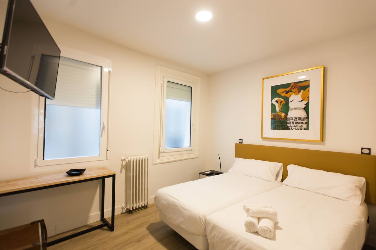 Hotellihuone, jossa on sänky, työpöytä, televisio ja seinällä kehystetty taulu.