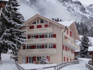 A multi-story hotel with balconies, a snow-covered landscape, and a mountainous backdrop. - Chalet Brunner 3 (Lauterbrunnen)