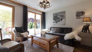 A modern living room with a glass coffee table, a sofa, a chair, and a lamp. - Chalet Brunner 3 (Lauterbrunnen)