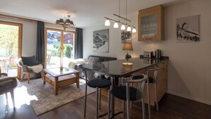 A modern kitchen with a bar area, wooden cabinets, and a large window offering a view of the outdoors. - Chalet Brunner 3 (Lauterbrunnen)