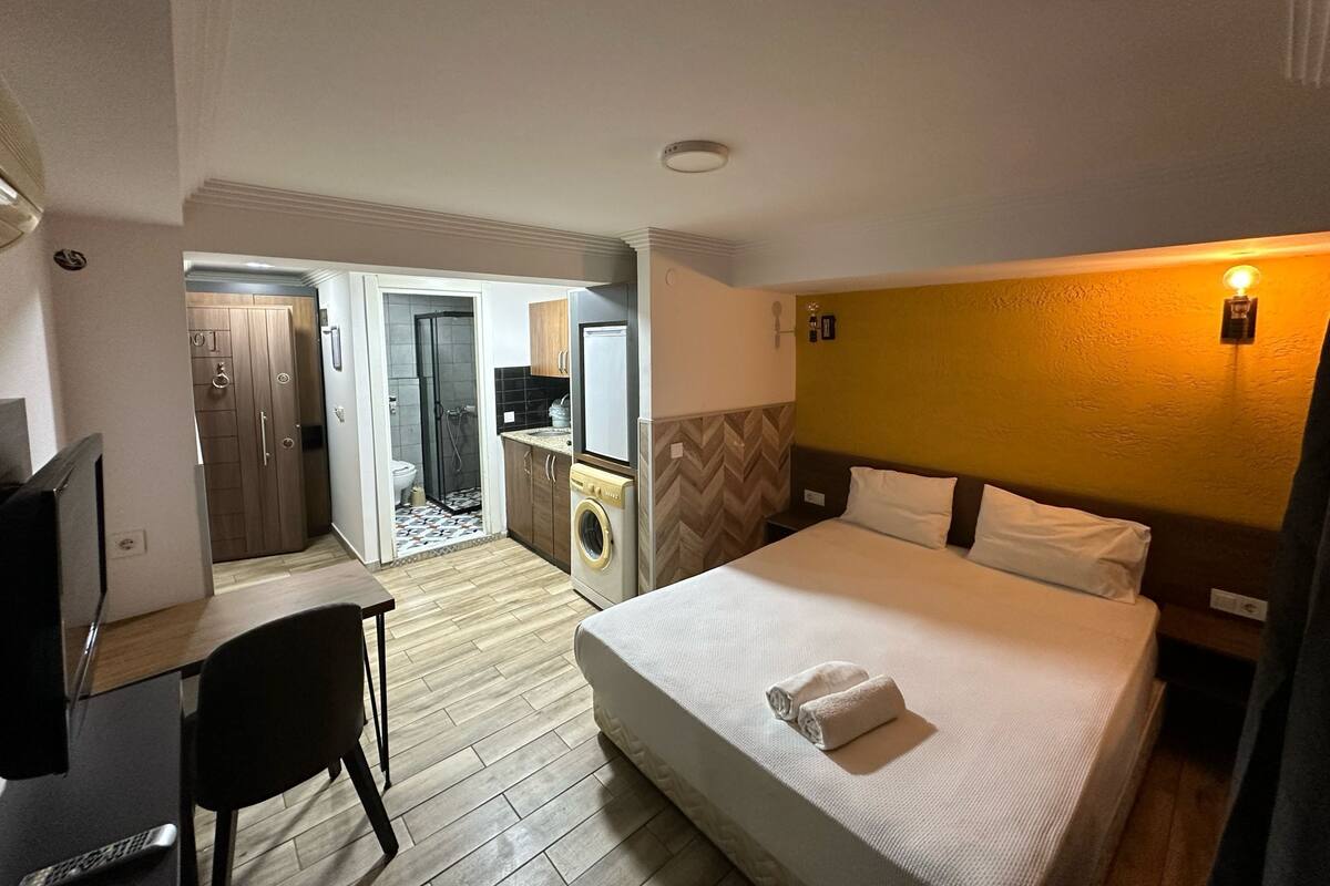 Ein Hotelzimmer mit Bett, Schreibtisch, Stuhl, Waschmaschine und einem Badezimmer mit Dusche und Toilette.