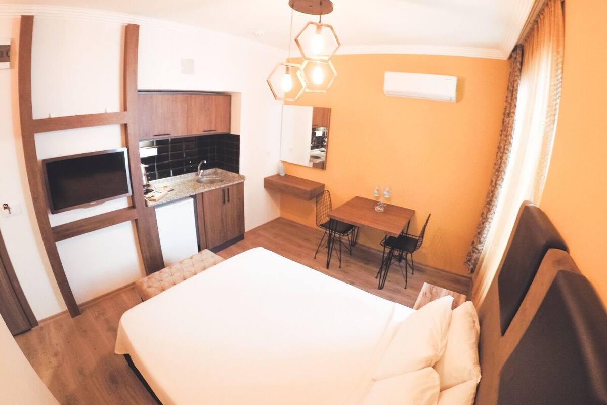 Ein kompaktes Hotelzimmer mit Bett, einer kleinen Küchenzeile, einem Essbereich und einem Badezimmer.