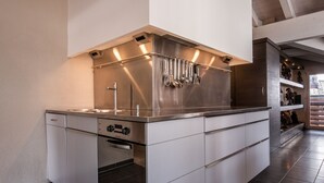 A modern kitchen with stainless steel appliances, a built-in oven, and a large island with a sink.