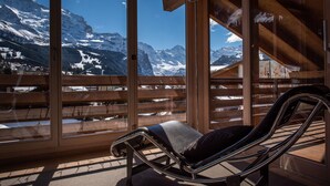 A sunlit room with a view of snow-capped mountains through large windows.