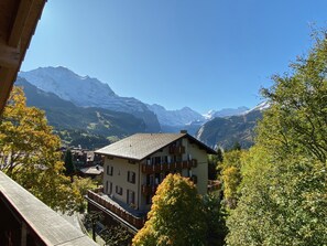 A mountain chalet with a sloped roof, wooden balconies, and a view of snow-capped mountains. - Chalet Bergfrieden Penthouse (Lauterbrunnen)