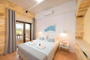A bedroom with a bed, a nightstand, a wall-mounted air conditioner, and a view through a glass door.