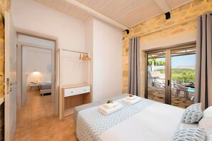 Een slaapkamer met een bed, nachtkastje, kaptafel en een badkamer zichtbaar door een geopende deur.