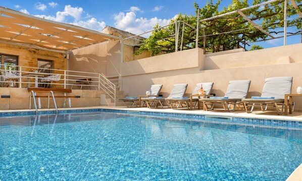 A swimming pool with lounge chairs and a pergola structure.