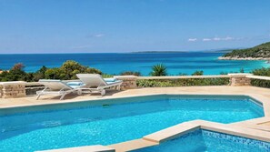 Une piscine avec des chaises longues et vue sur la mer.