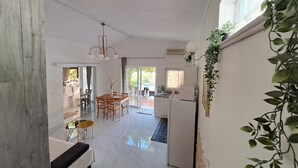 Un amplio espacio de sala con una mesa de comedor, un sofá y una zona de cocina con refrigerador.