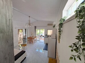 Un amplio espacio de sala con una mesa de comedor, un sofá y una zona de cocina con refrigerador.