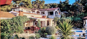Uma casa de pedra de vários andares com um pátio, área de estar ao ar livre e piscina.