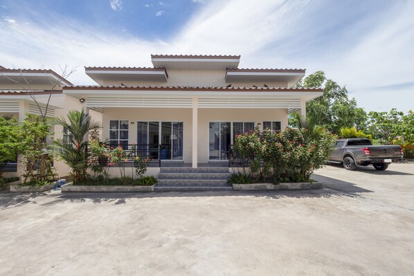 A two-story house with a flat roof and a covered front porch. - OYO 1048 Home and Garden Resort (Bang Lamung)