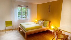 A bedroom with a bed, bedside tables, a chair, and a window. - At home in the love nest (Innsbruck)