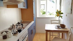 A kitchen with a stove, sink, and a dining table with chairs. - At home in the love nest (Innsbruck)