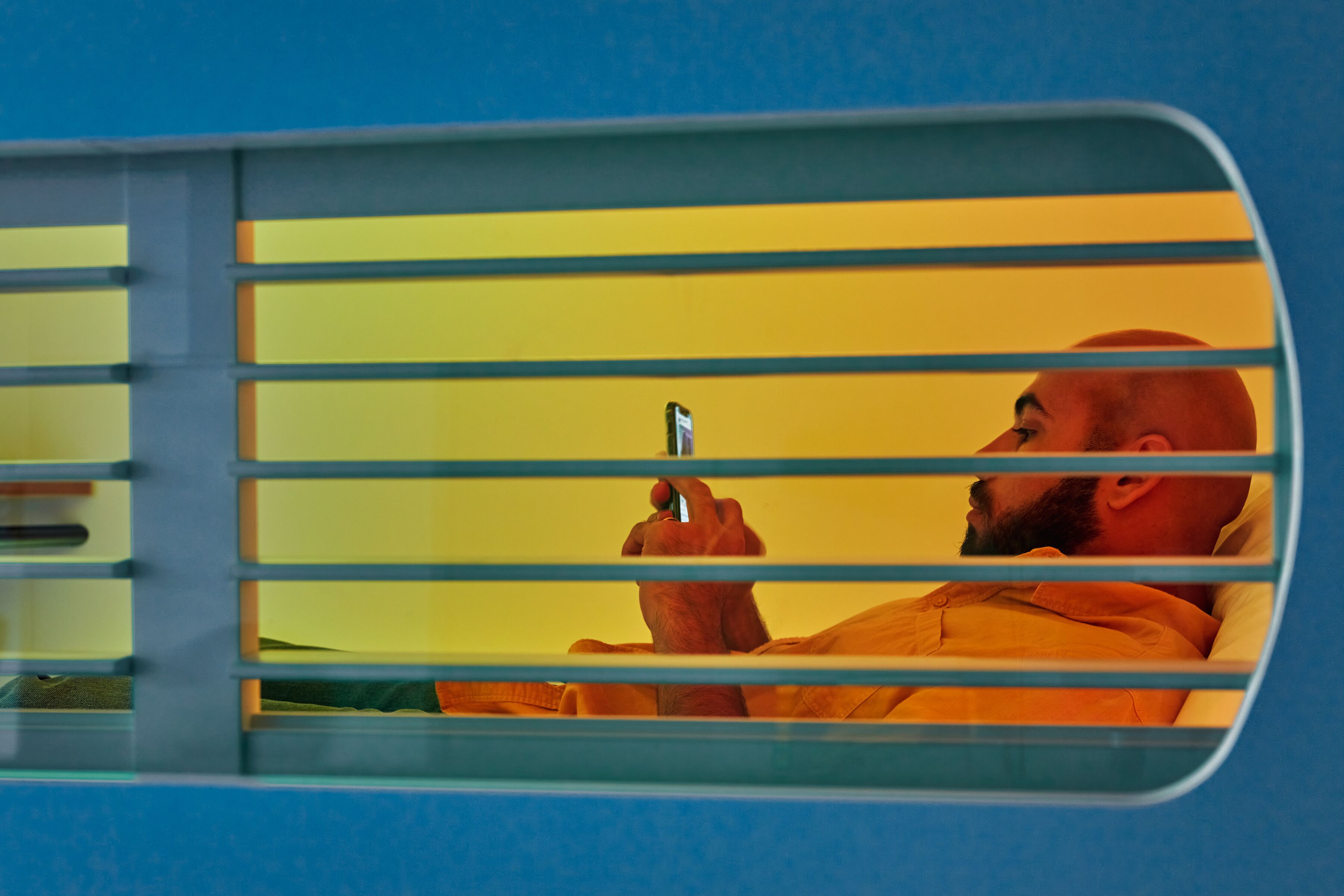 A person sitting in a vehicle with horizontal bars, holding a mobile device.