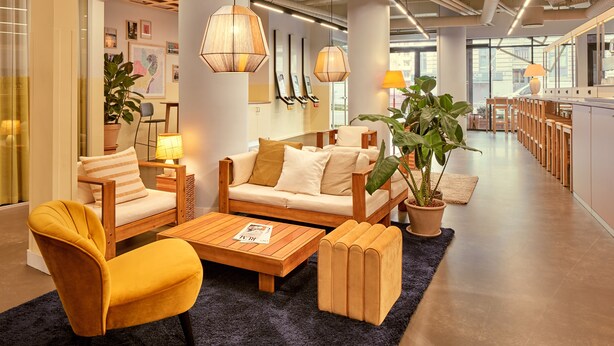 Un hall d’entrée moderne avec un canapé, des fauteuils, une table basse et une plante en pot.