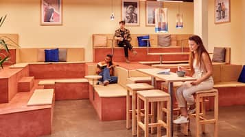 A modern lounge area with seating arrangements, tables, and a coffee station.