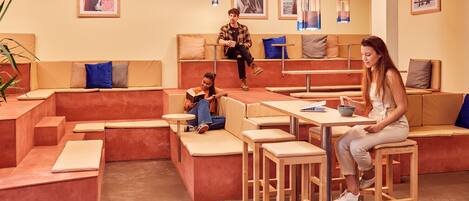 A modern lounge area with seating arrangements, tables, and a coffee station.
