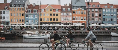 A canal with boats, colorful buildings, and people riding bicycles.