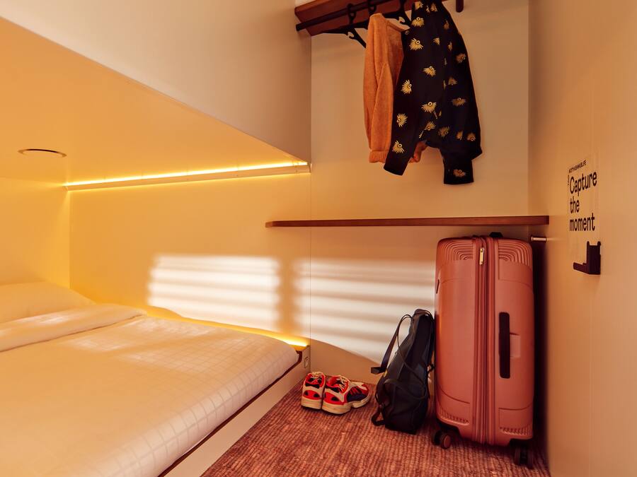 A bedroom with a bed, a suitcase, and a jacket hanging on the wall.