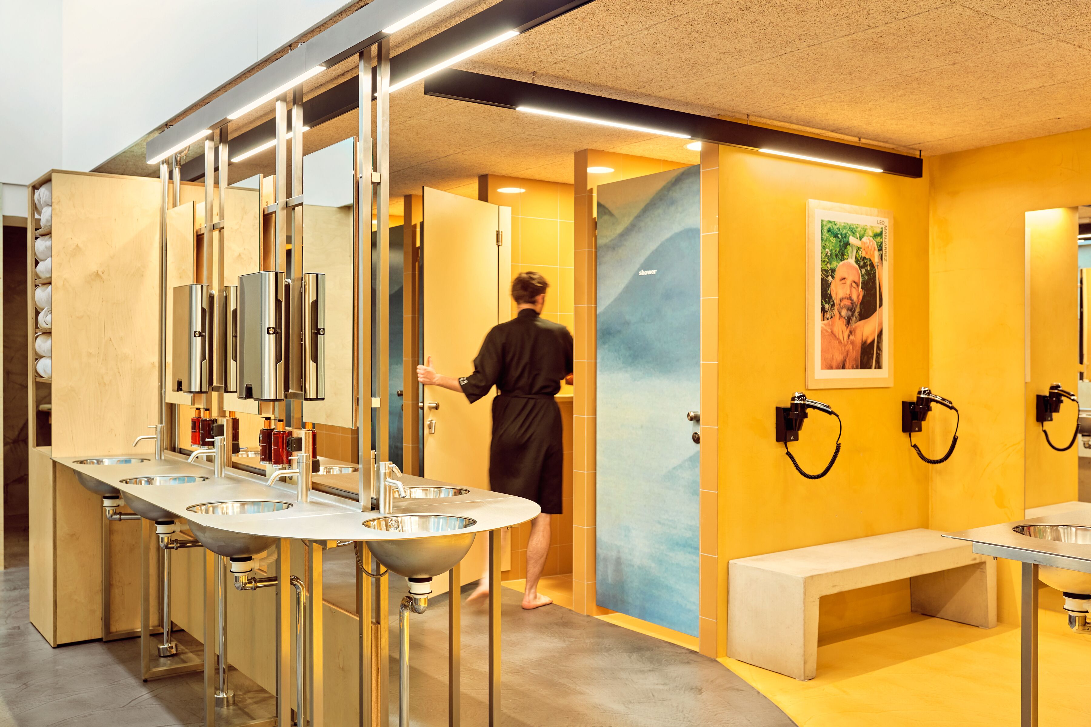 A modern bathroom with multiple sinks, a bench, and a mirror.