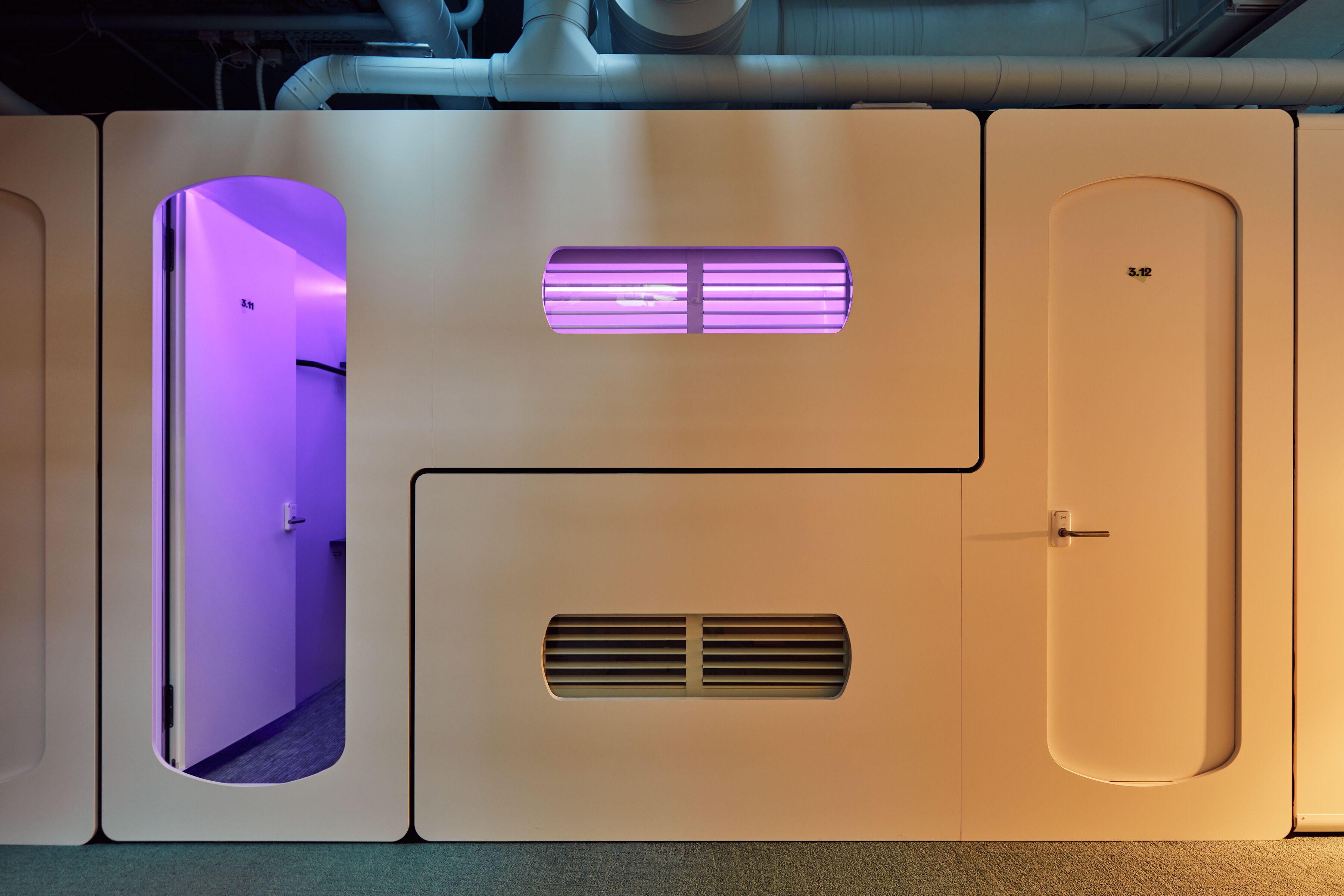 A modern, minimalist room with a purple-lit door, a ventilation panel, and a small window.