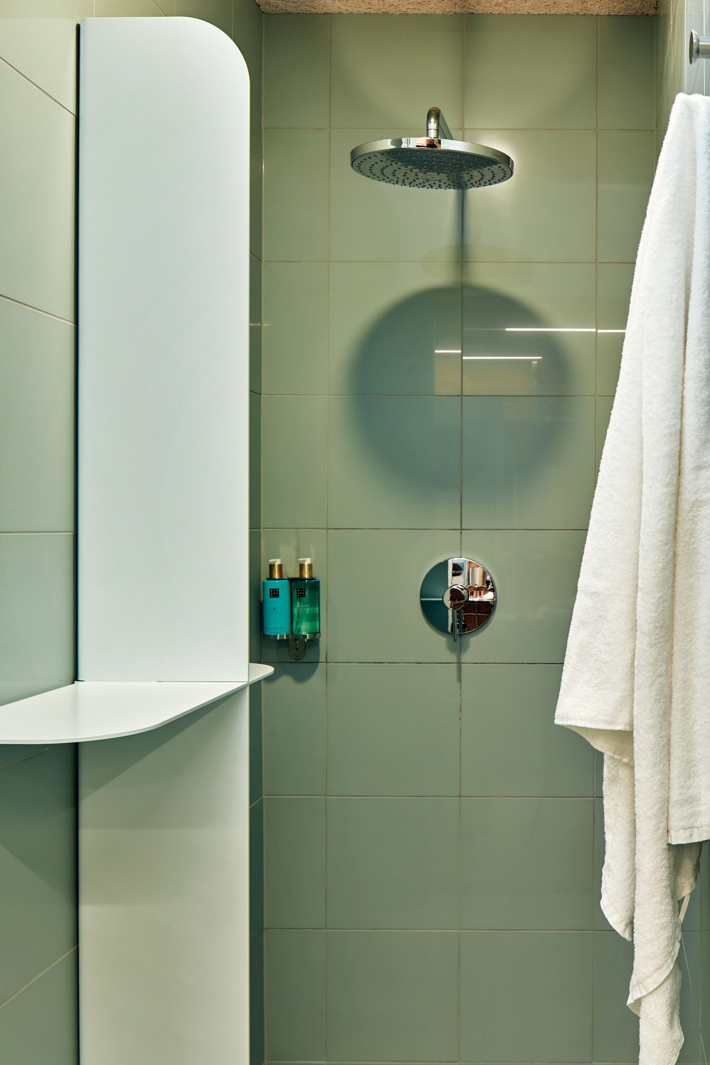 Un baño moderno con ducha, un perchero y dos dispensadores de jabón.