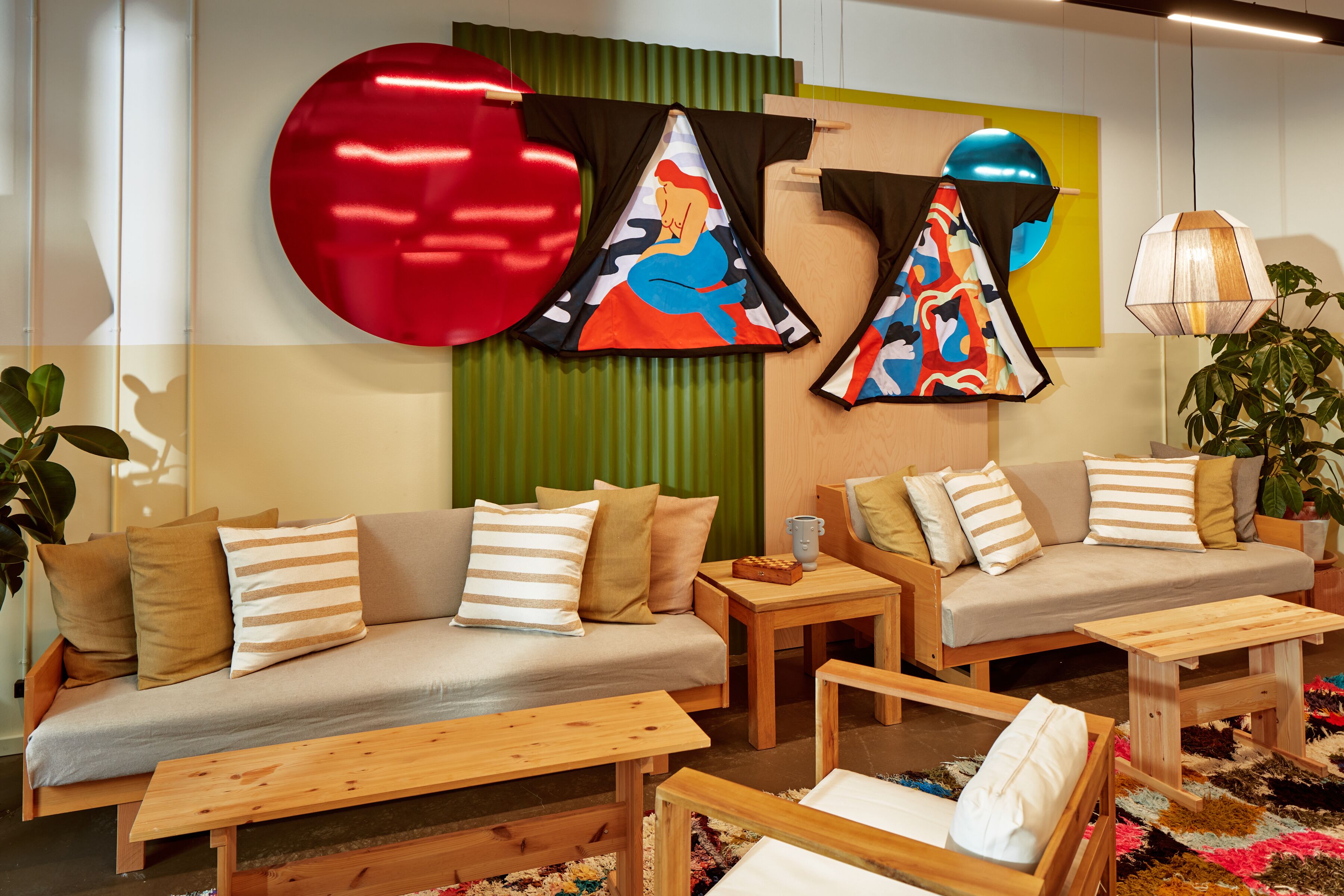 Una sala de estar moderna con un sofá, dos mesas auxiliares de madera y una mesa de centro. Hay almohadones decorativos y una alfombra colorida en el suelo.