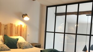 A bedroom with a large bed, wooden headboard, and a window with frosted glass. - Charming stone house in the countryside (Céret)