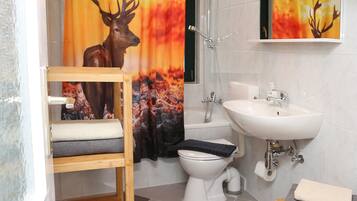 Ein Badezimmer mit Holzregal, Waschbecken, Toilette und Dusche.