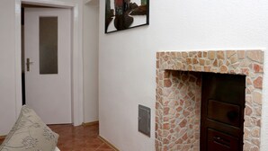 Ein Korridor mit Kamin aus Stein, einer Tür und einem gerahmten Kunstwerk an der Wand.