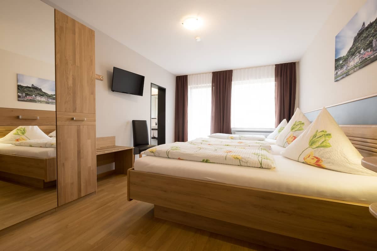 A modern hotel room with a wooden bed, a flat-screen TV, and a large window with curtains.