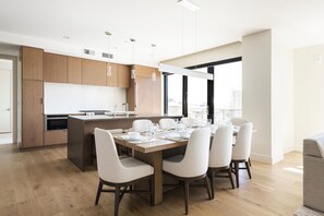 A modern kitchen with wooden cabinets, a built-in oven, and a dining area with a wooden table and chairs.