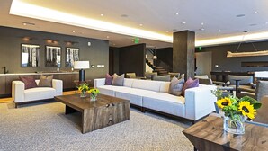 Een moderne lobby met een bank, salontafel en stoelen. Er hangt kunst aan de muren en er is een trap op de achtergrond te zien.
