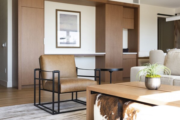 Una sala de estar moderna con un sillón de cuero, una mesa de centro de madera con una planta y un sofá.