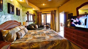 A bedroom with a large bed, a sofa, a television, and a dresser.