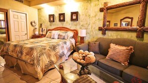 A bedroom with a bed, a sofa, a coffee table, and a mirror.