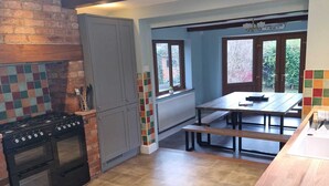 Une cuisine avec un mur en briques, un plafond en bois et une fenêtre.