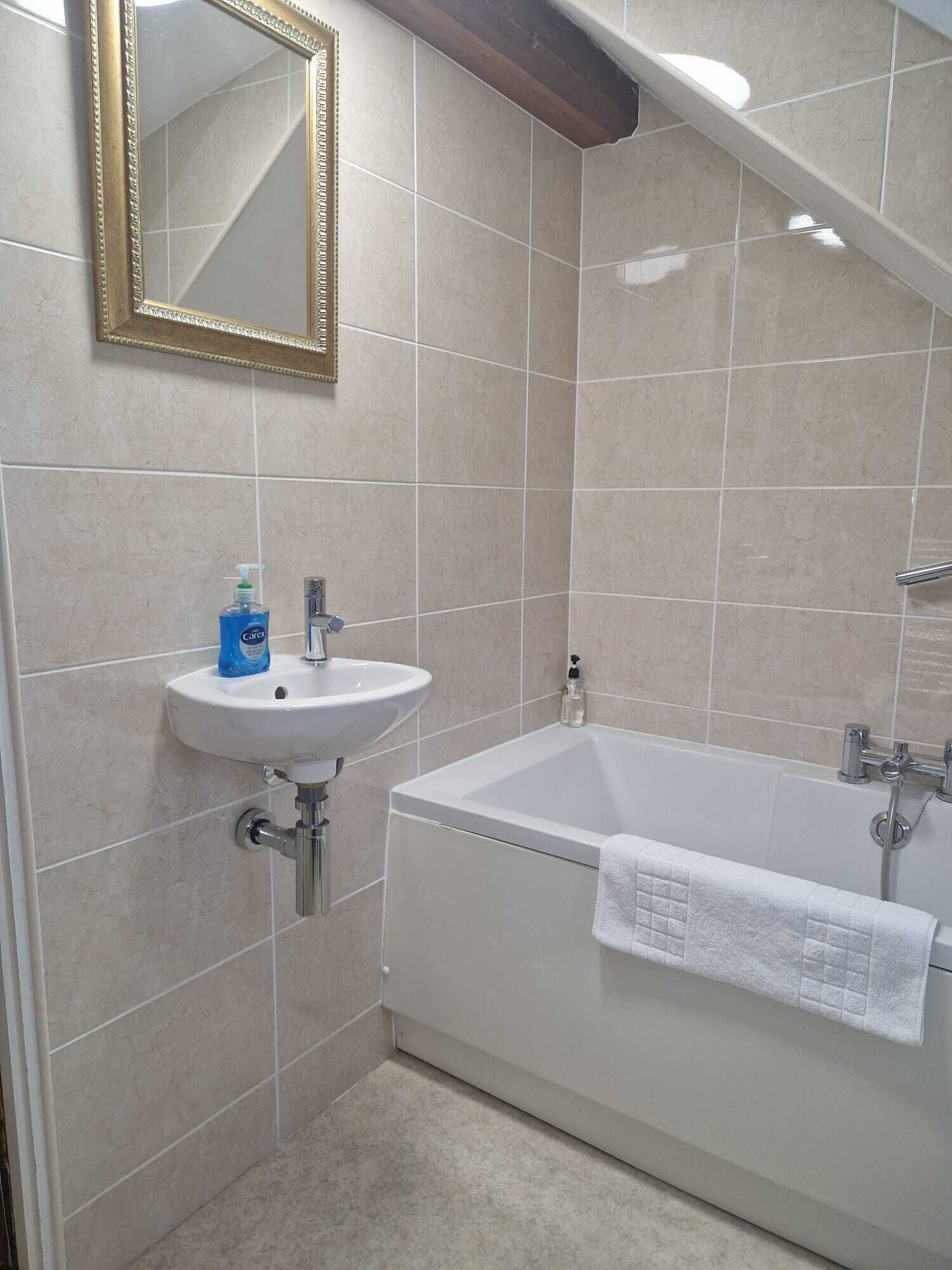 A bathroom with a white sink, a bathtub, and a mirror.
