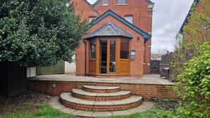 Une maison en briques avec un petit porche et un escalier menant à une porte.