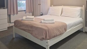Une chambre à coucher avec un lit, une table de chevet et une fenêtre avec des rideaux.