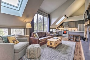 A spacious living area with a loft kitchen, large windows, and a cozy seating arrangement.