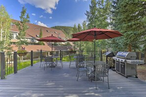 A deck with outdoor furniture, umbrellas, and a grill. - Hot Tub + Ski Shuttle Access: Keystone Condo! (Keystone)