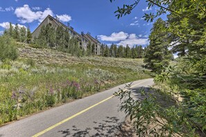 A road curving through a hilly area with a multi-story building on the left. - Hot Tub + Ski Shuttle Access: Keystone Condo! (Keystone)