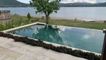 A rectangular swimming pool with a clear view of a lake and distant mountains.