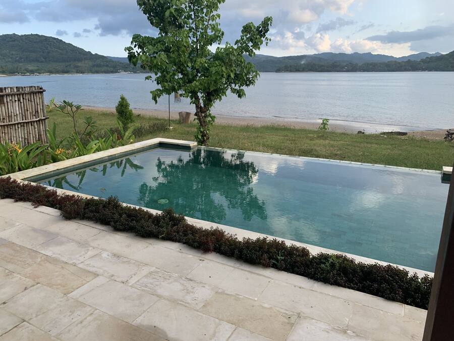 A rectangular swimming pool with a clear view of a lake and distant mountains.