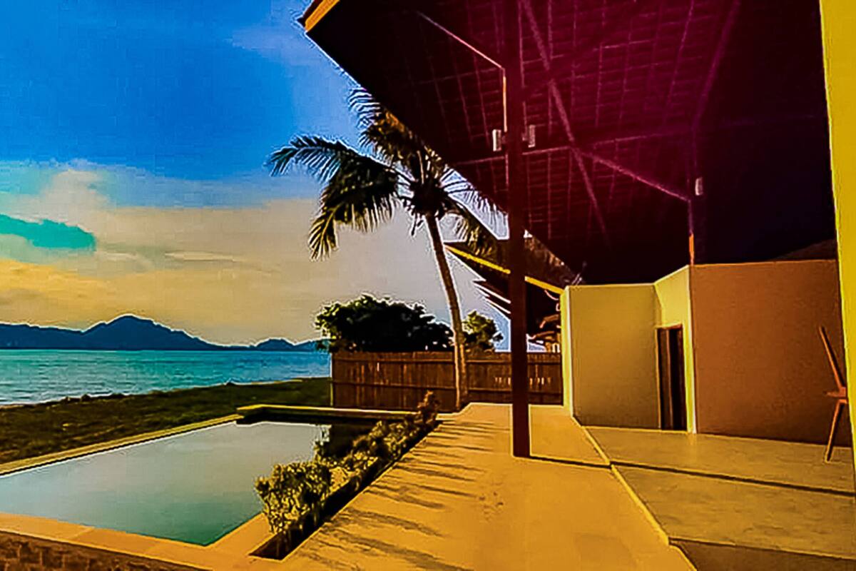 A modern building with a pool, a view of the ocean, and mountains in the background.