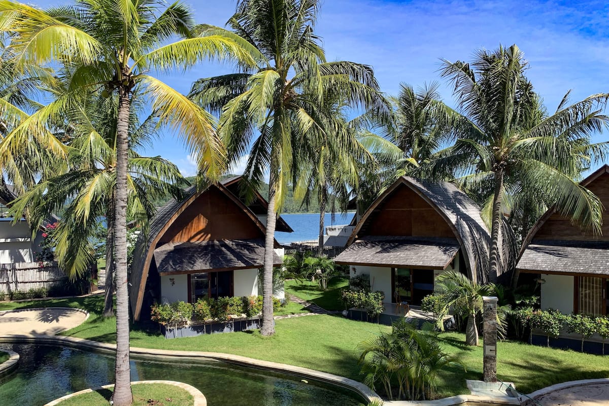 A resort with multiple bungalow-style cottages, a central swimming pool, and lush tropical landscaping.