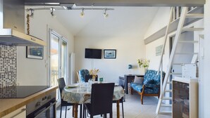 Una cucina moderna con zona pranzo, TV a parete e una scala che conduce a un piano superiore.